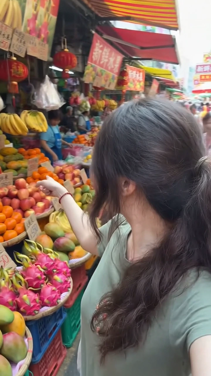 Chica comprando fruta en un mercado, vista sobre el hombro